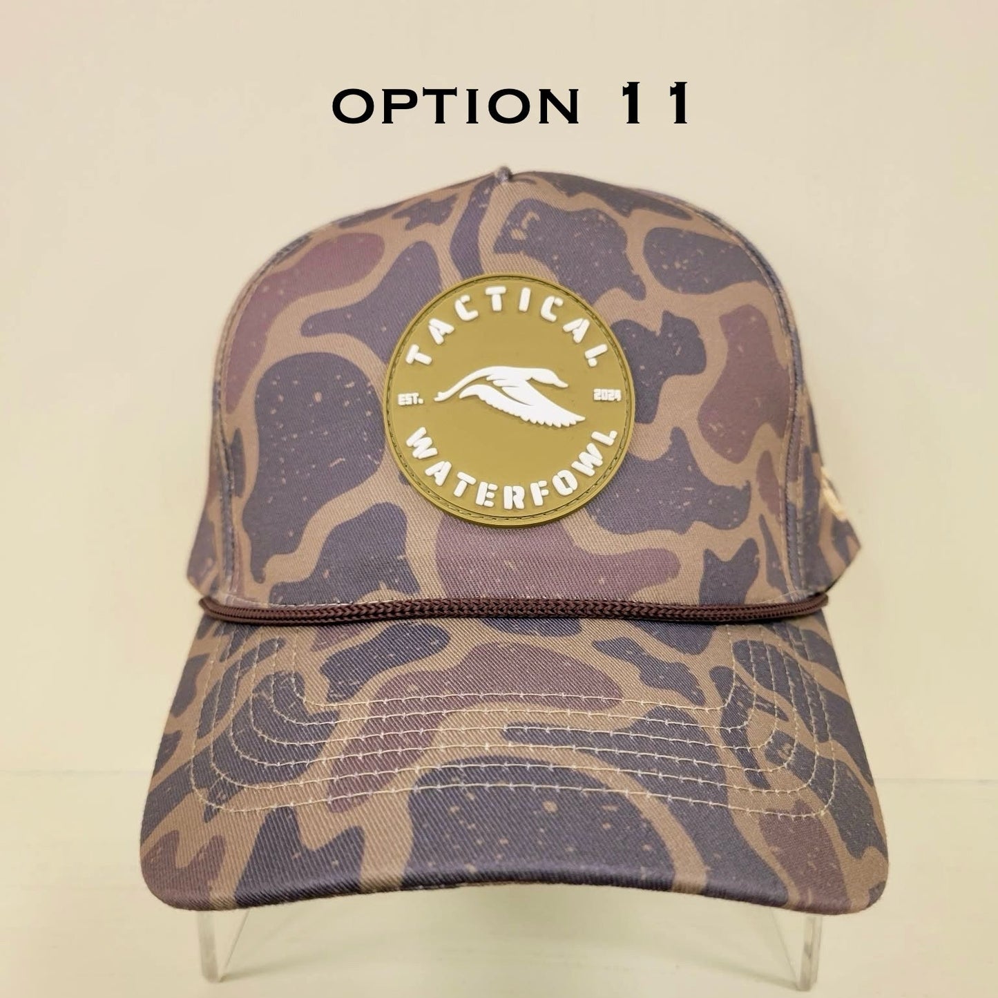 Camouflage-patterned cap with a gold logo on a beige background