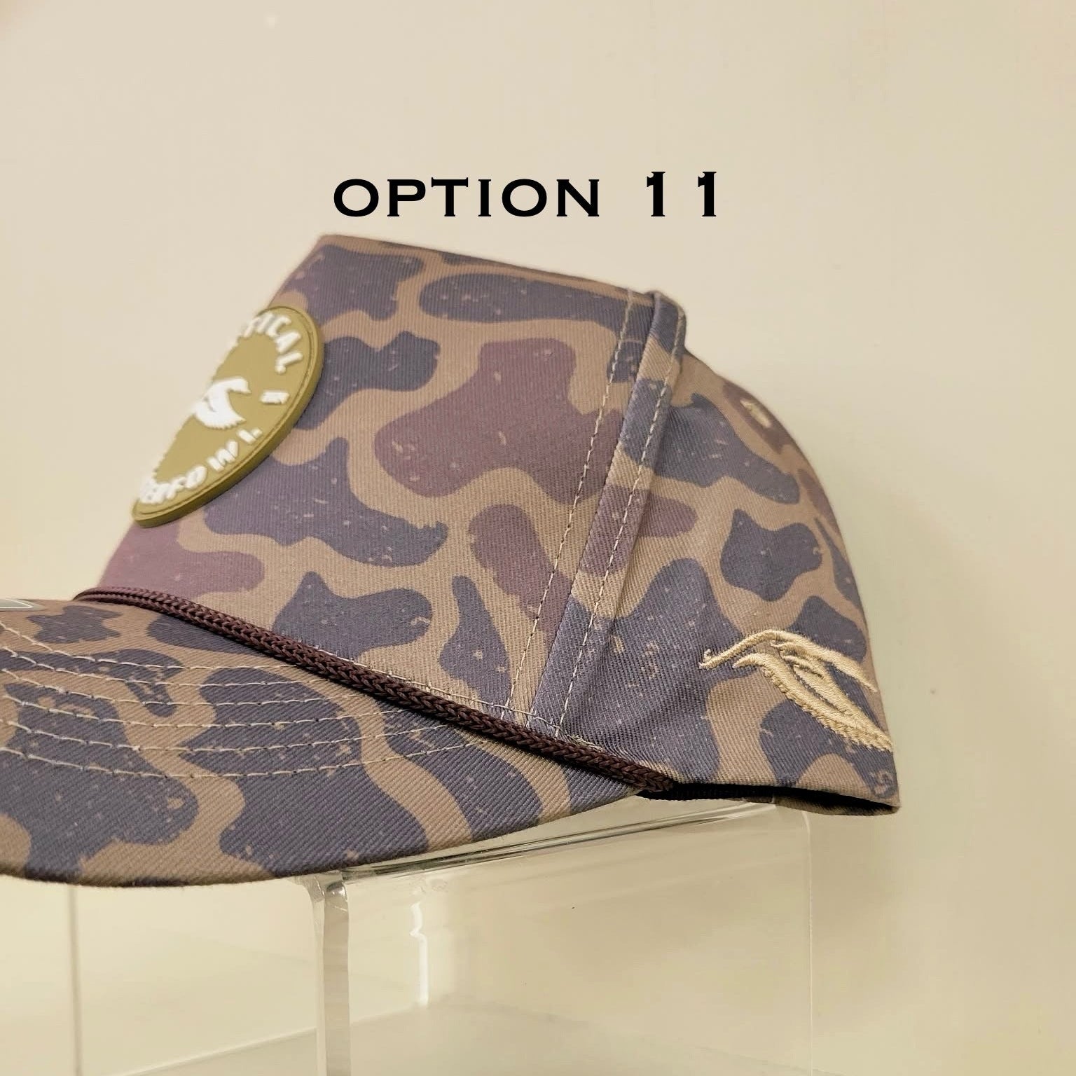 Camouflage-patterned hat with a patch on a beige background, labeled 'OPTION 11'.