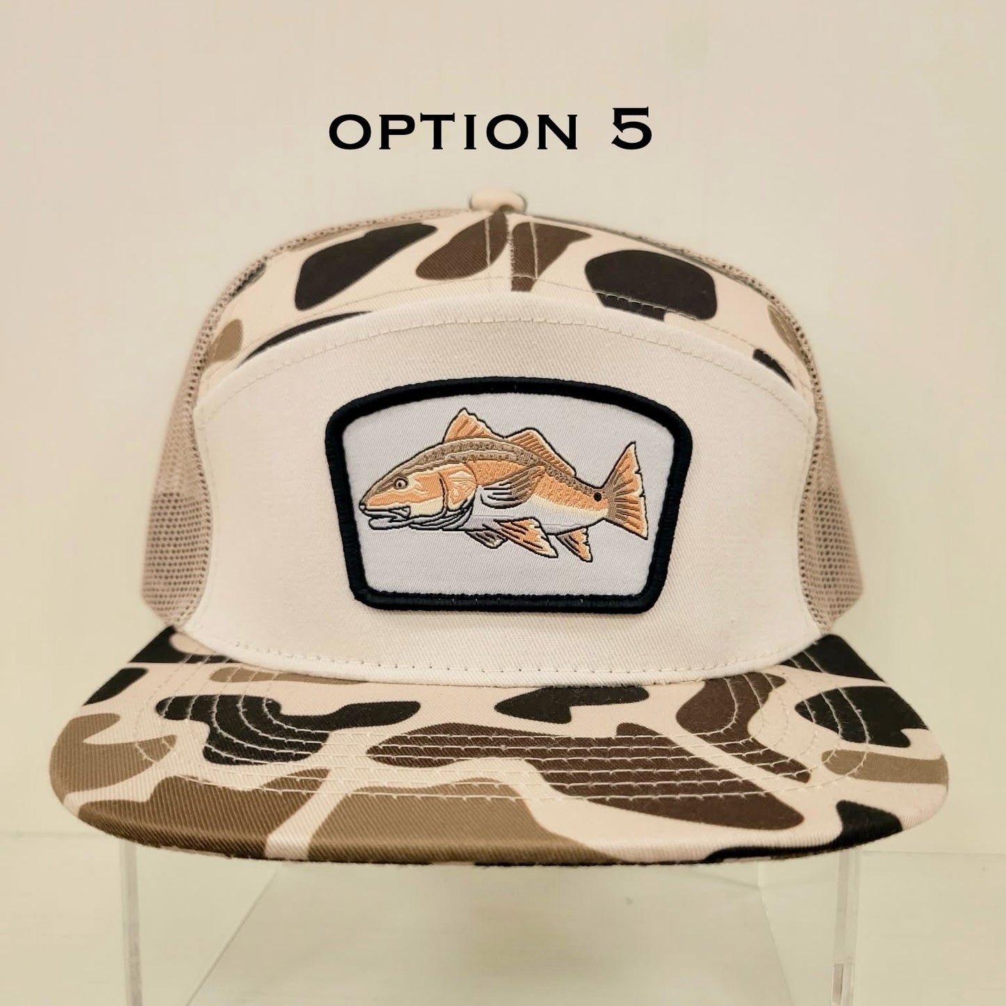 Trucker hat with fish patch and camouflage brim on a beige background