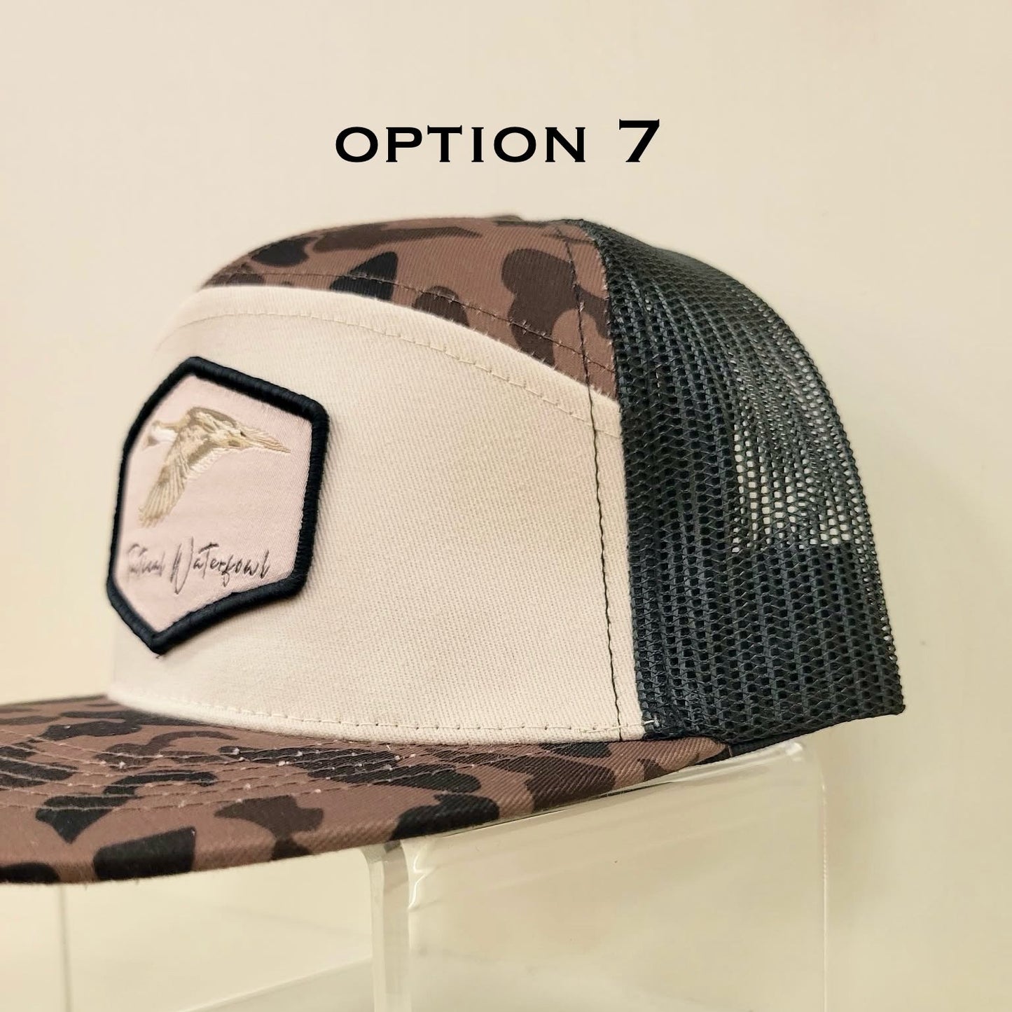 Camouflage trucker hat with a patch on a clear stand