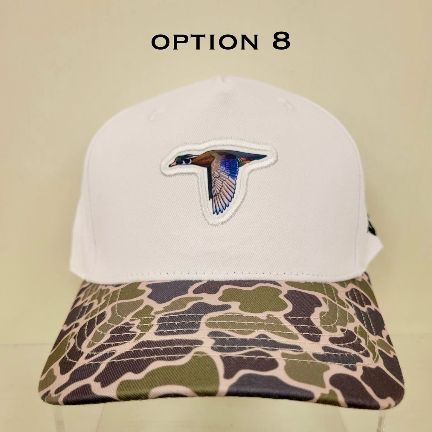 Cap with camouflage bill and white top on a beige background