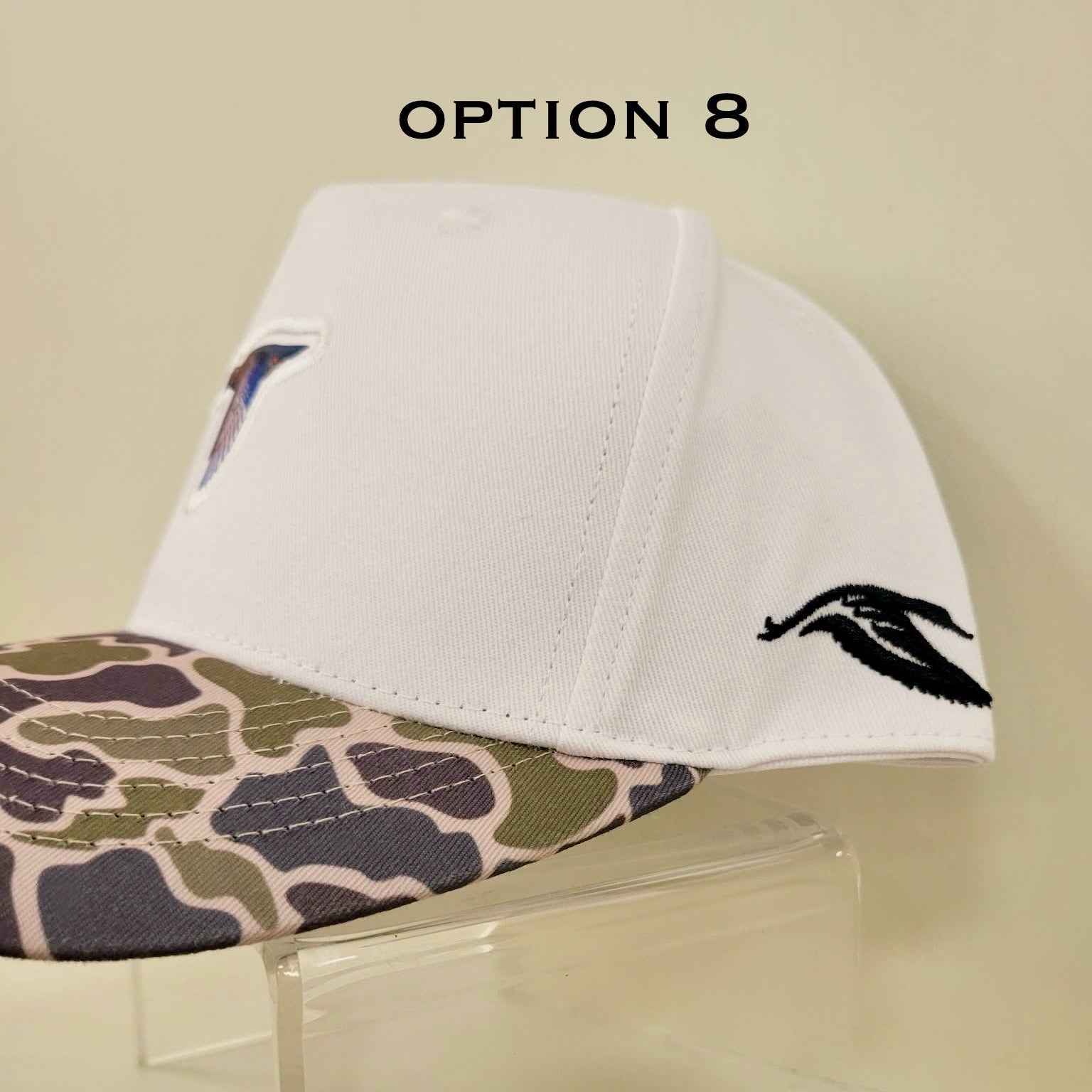 White cap with camouflage brim and black logo on a beige background