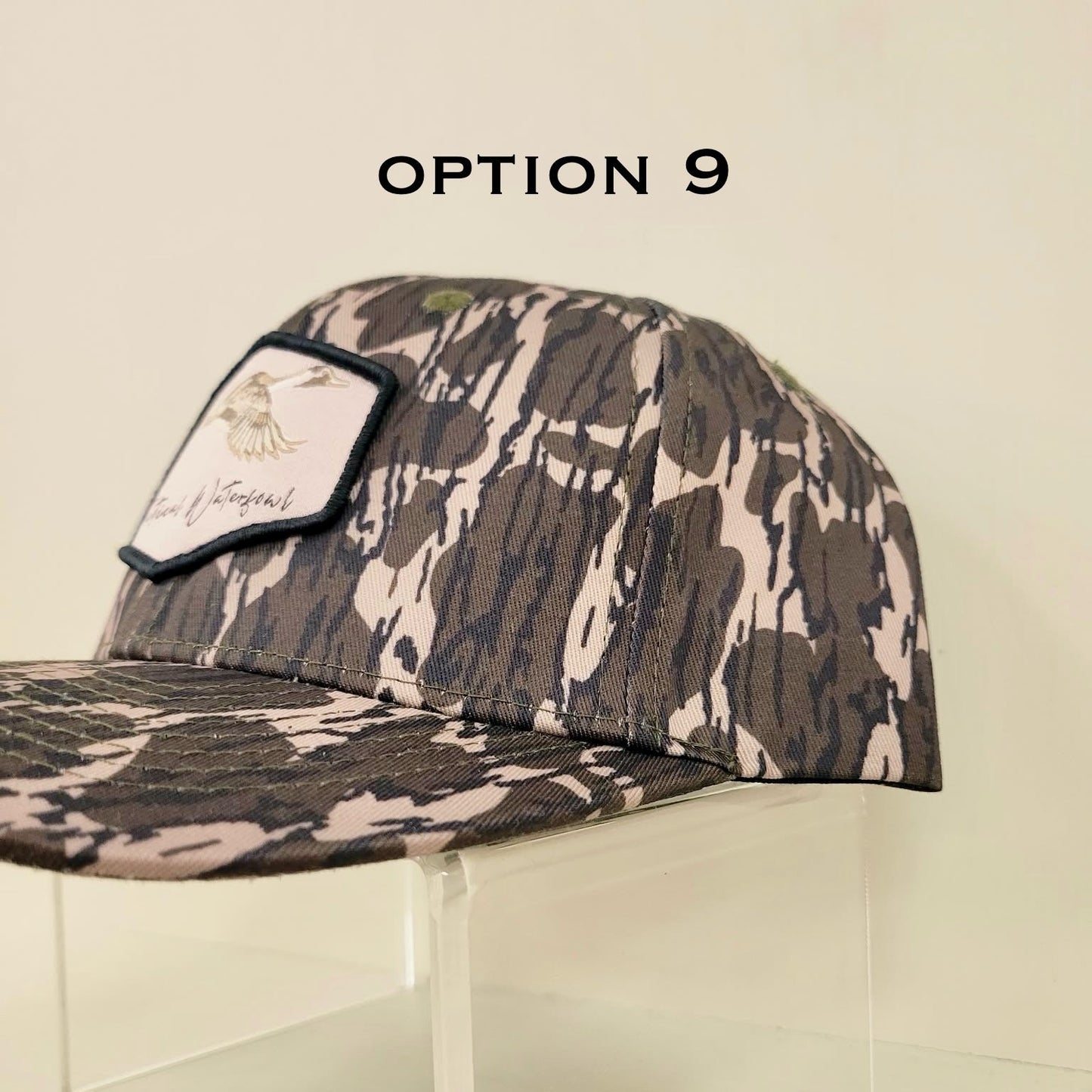 Camouflage baseball cap on a clear stand with 'Option 9' text.