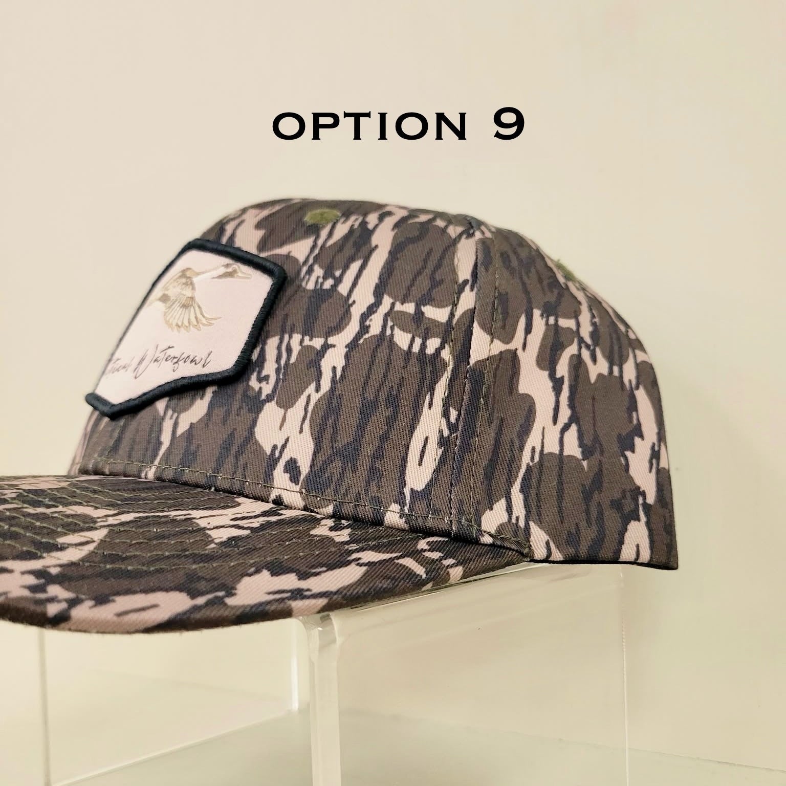 Camouflage baseball cap on a clear stand with 'Option 9' text.