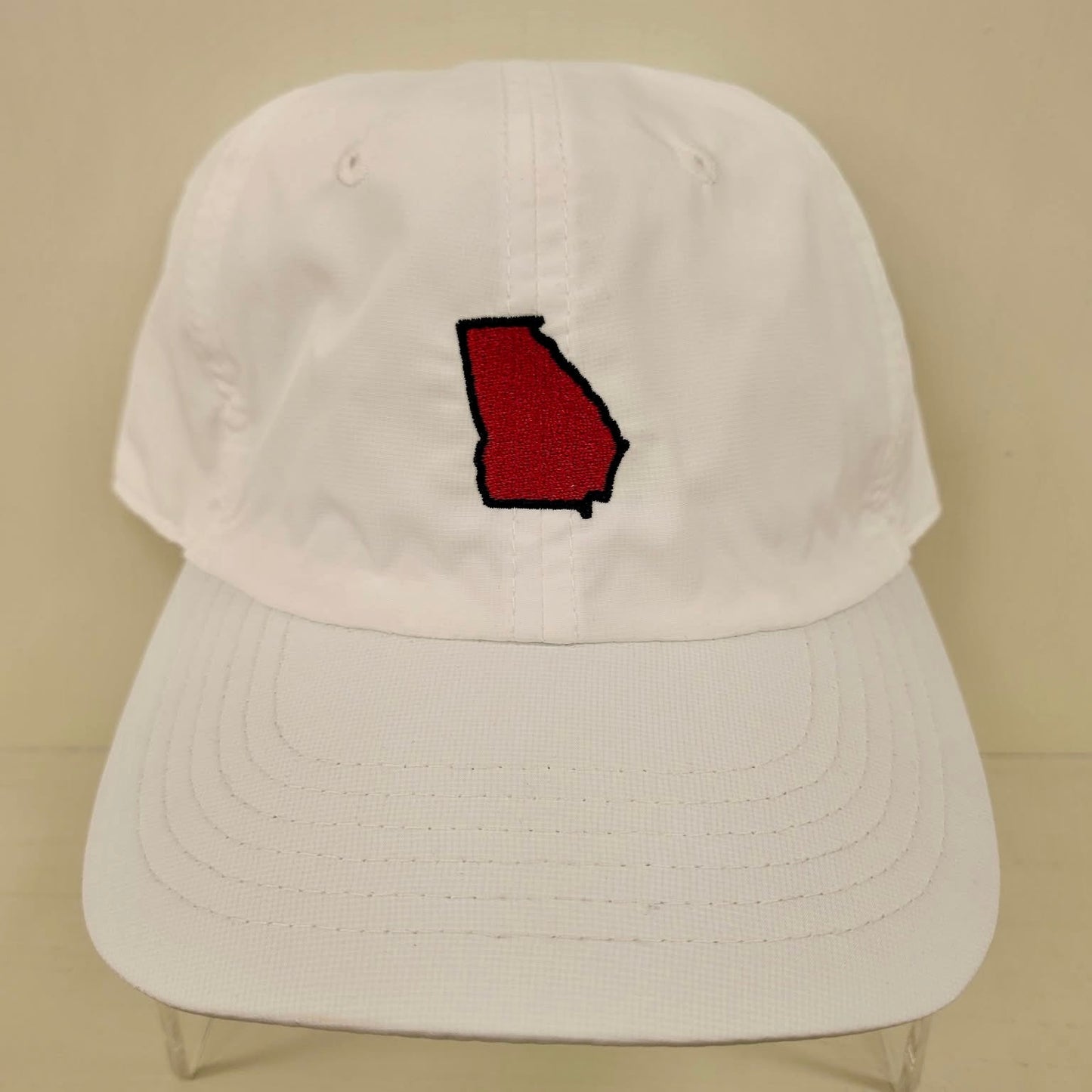 White cap with a red and black logo on a beige background